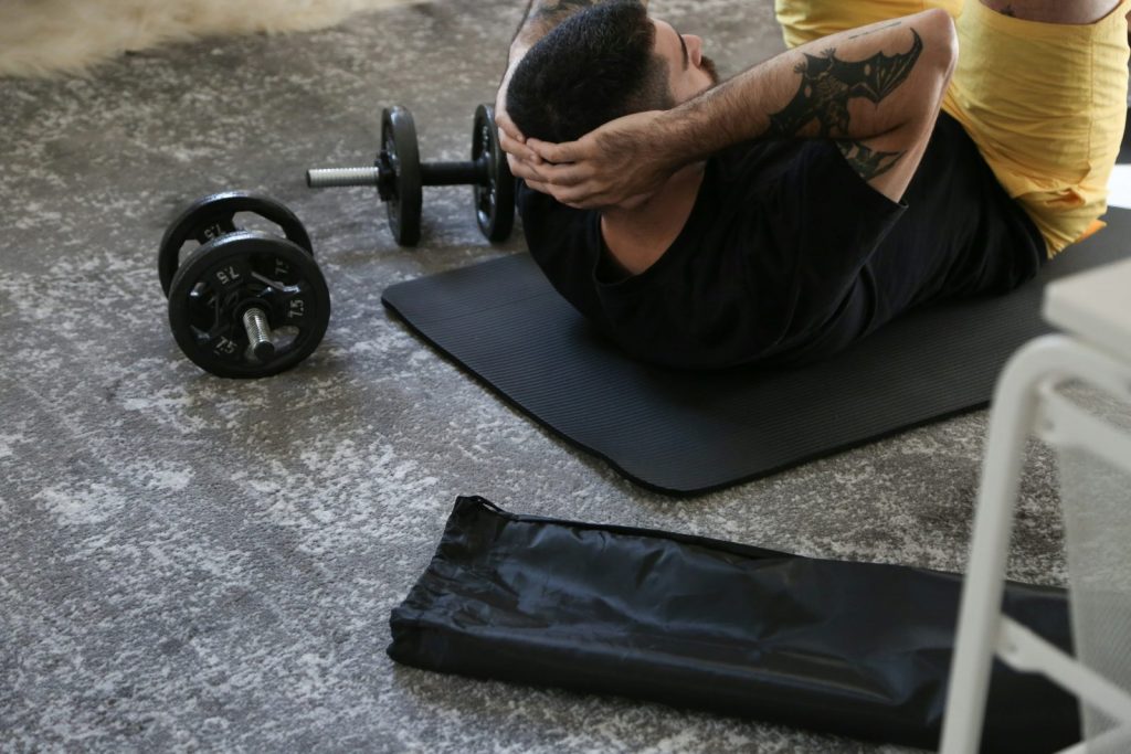 man doing core strength training exercises for weight loss with dumbbells nearby
