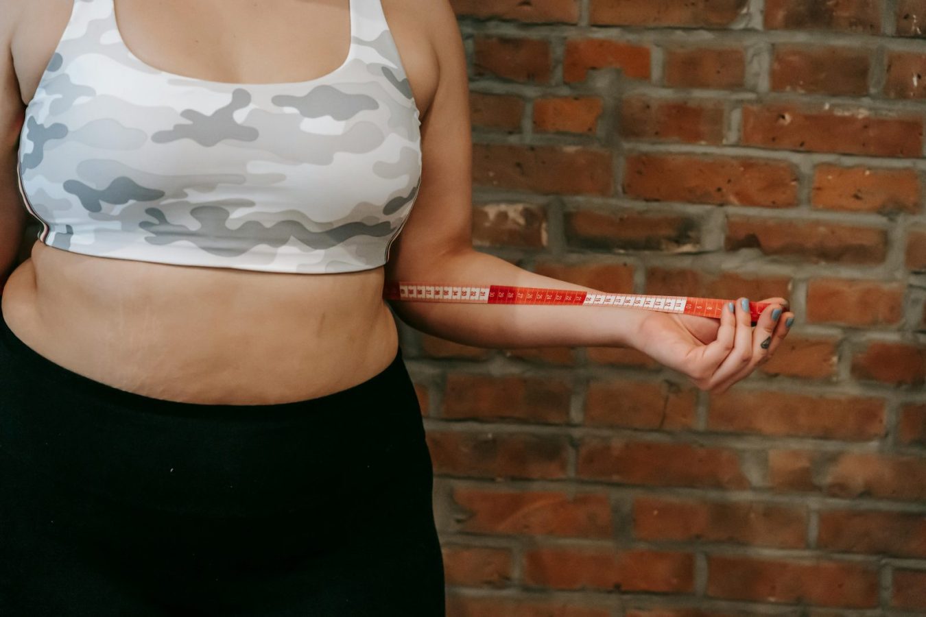 Middle-aged woman measuring her belly with a tape measure – how to get rid of belly fat after 40