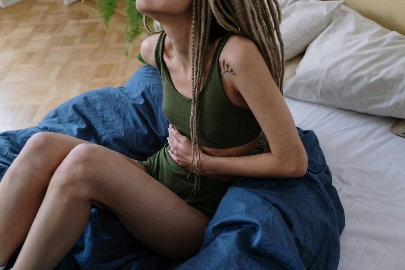 why do my legs hurt during period – woman sitting on bed with cramps that radiate to legs