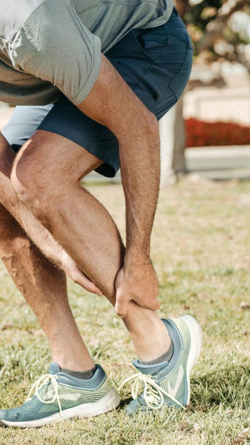 why do my legs hurt so bad - man holding his lower leg in pain outdoors
