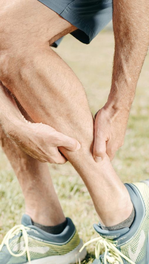 man massaging calf muscles after workout to reduce soreness