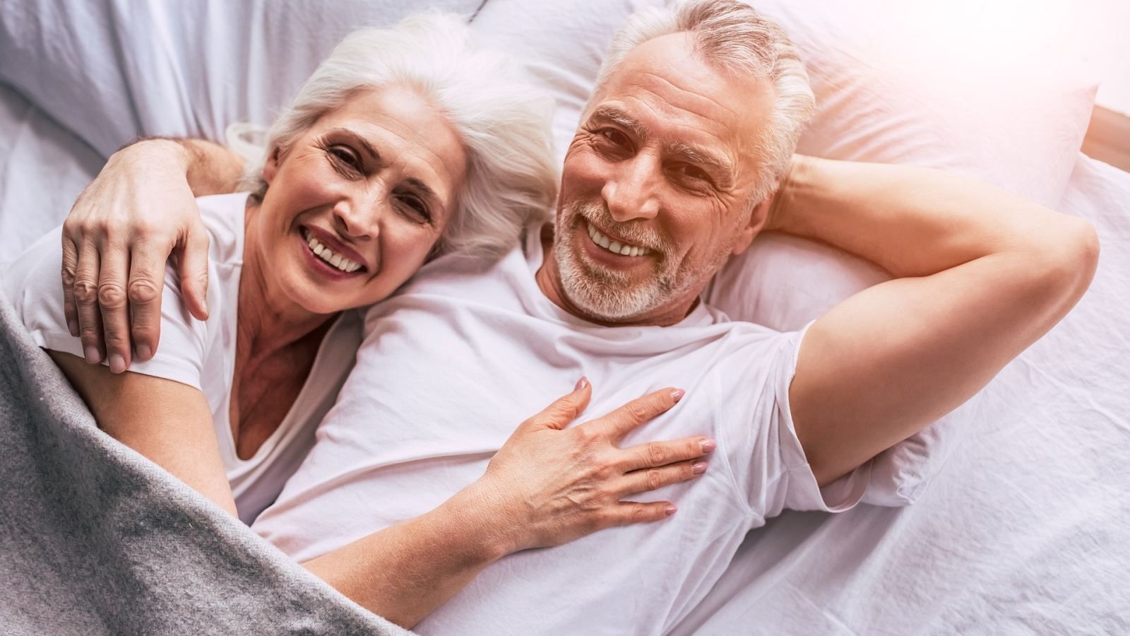 Happy older couple relaxing in bed on a bright morning
